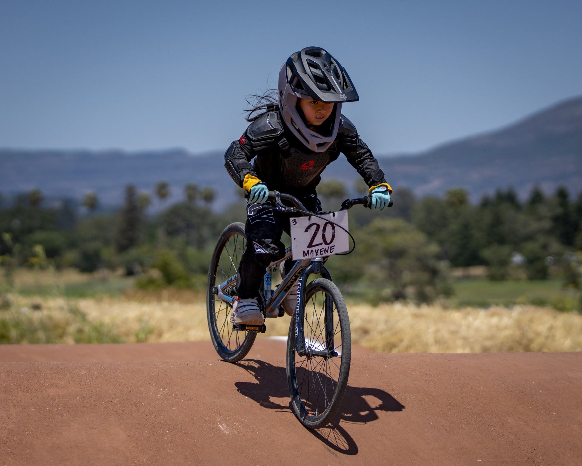 Max with her bike and number on a hill